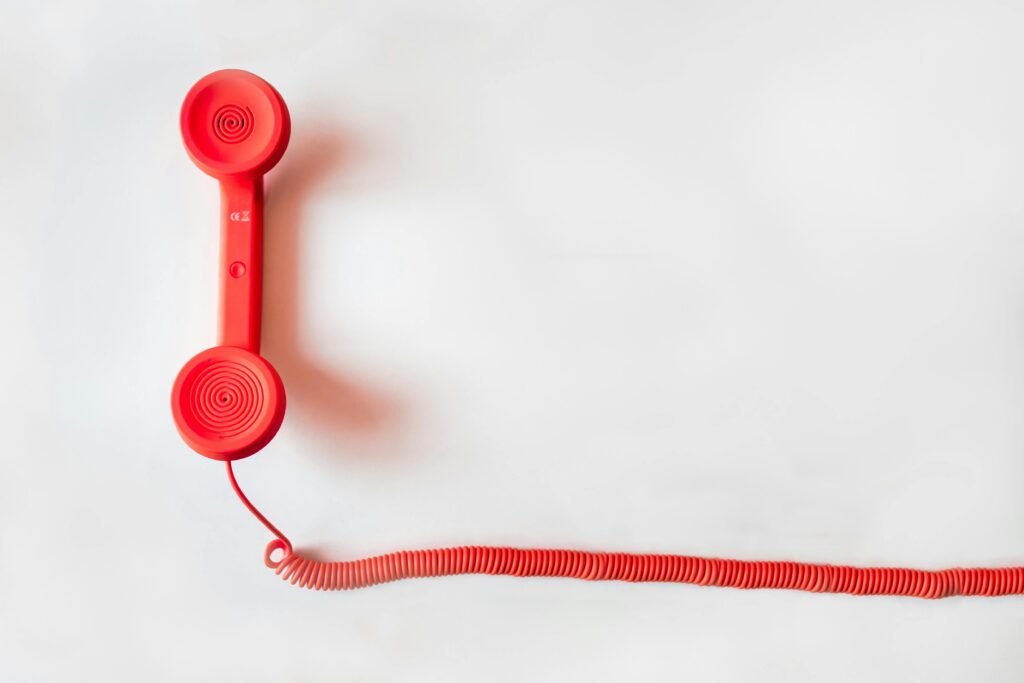 pexels-photo-33999 Vintage red phone handset with coiled cable on a clean white background, classic communication device.